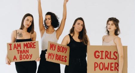 women standing while holding girl empowering placards